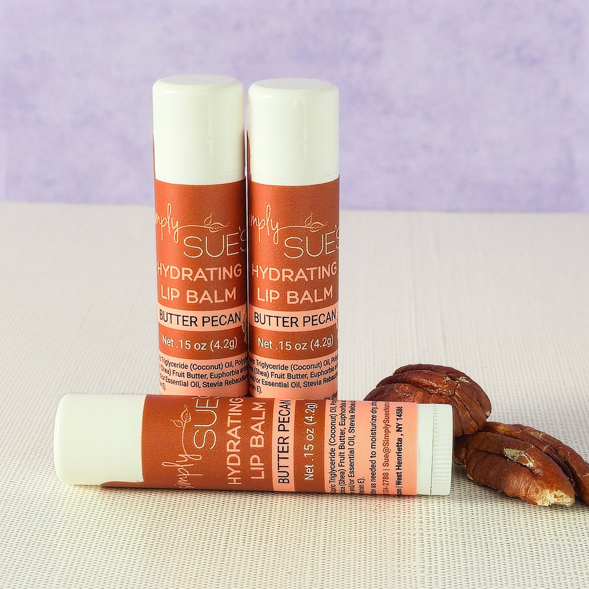 Butter pecan lip balm tubes by Simply Sue’s with pecans on a neutral background