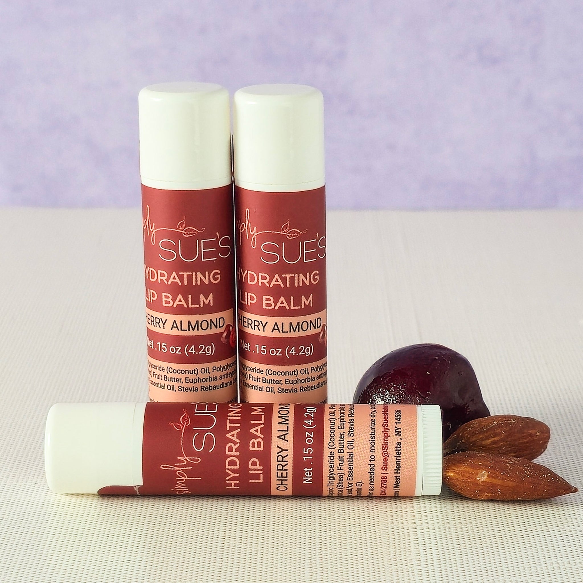 Cherry almond lip balm tubes by Simply Sue’s with cherries and almonds on a neutral background