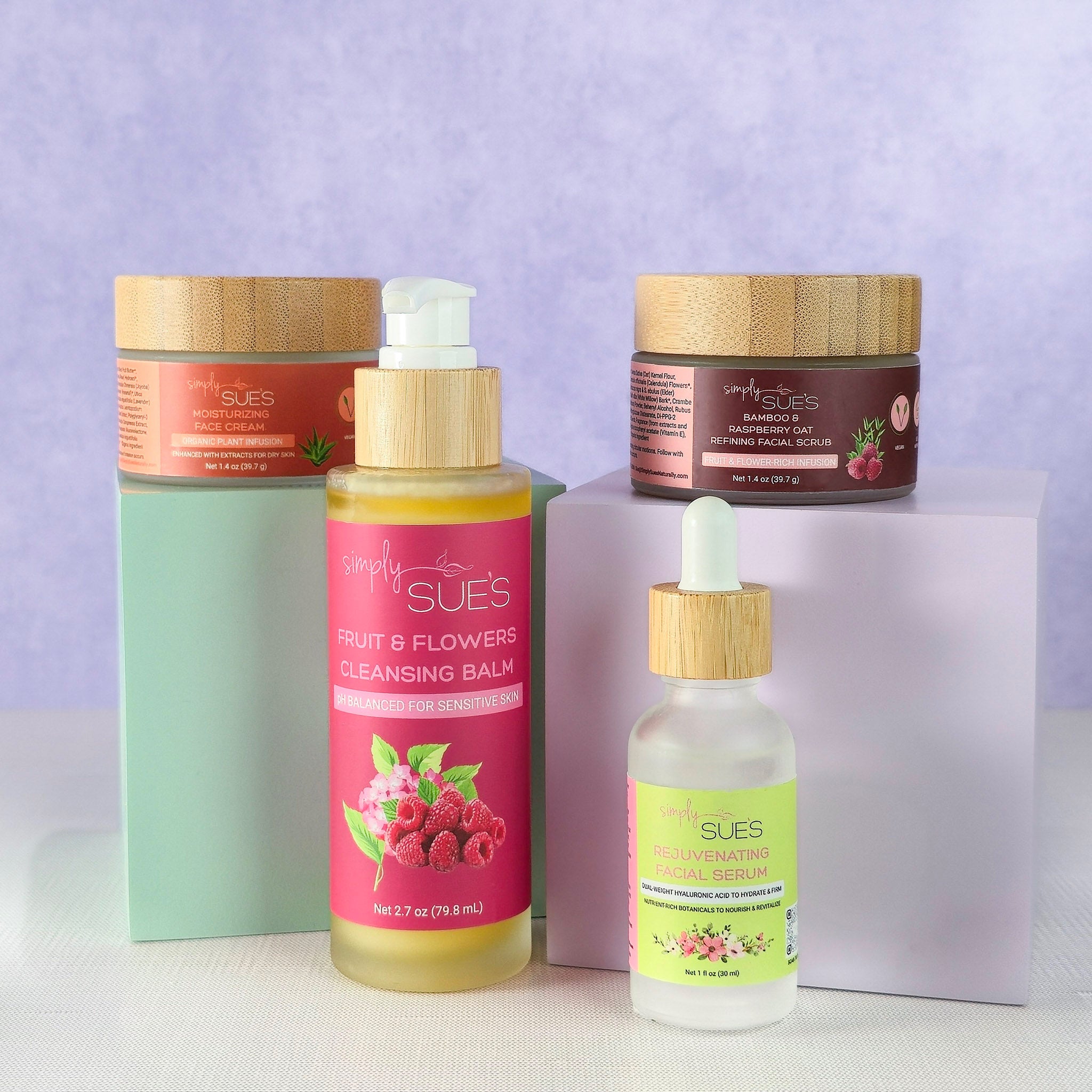 Natural skincare set with cleansing balm, serum, face cream, and exfoliating scrub in glass and bamboo packaging on a soft purple background, complete nourishing skincare ritual