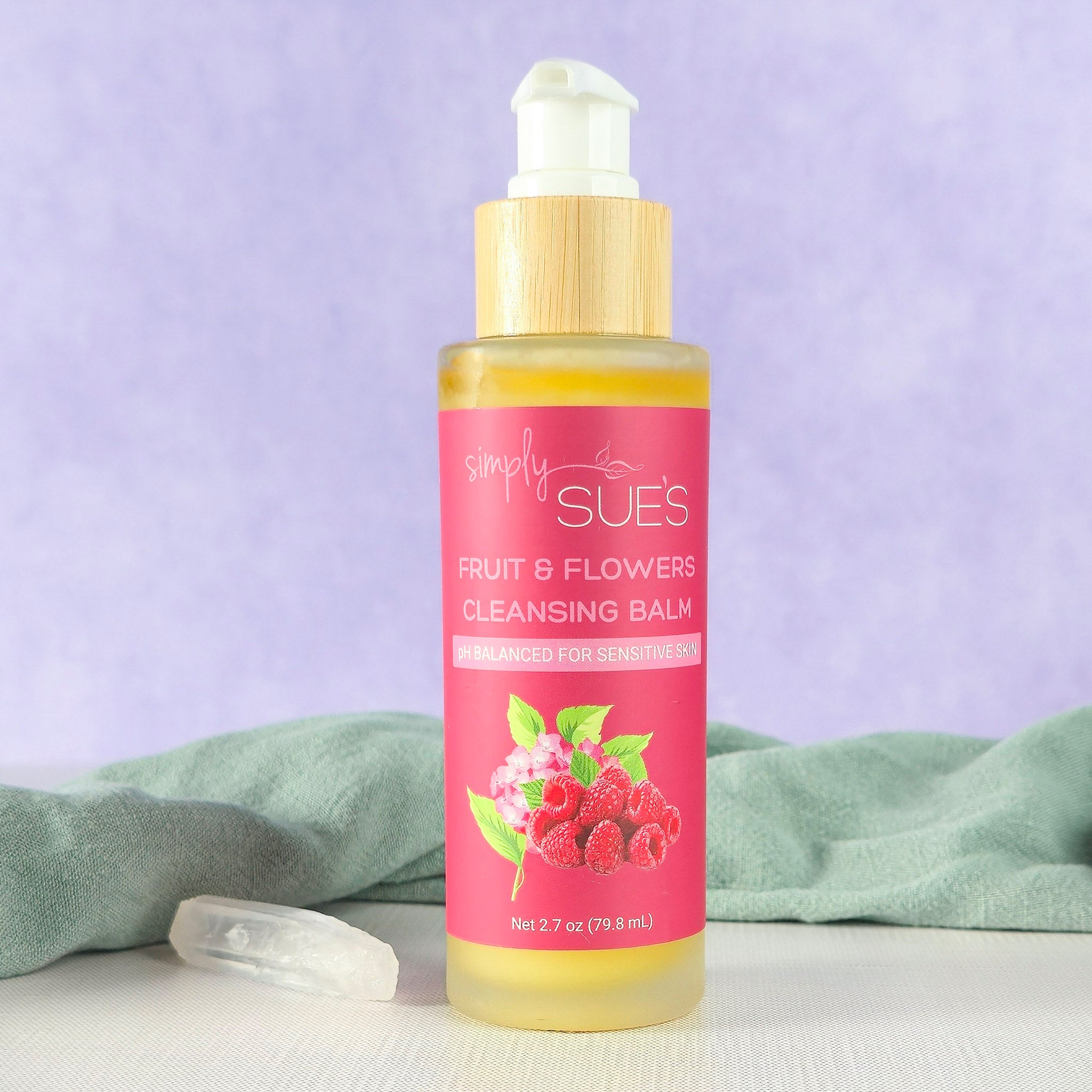 Natural cleansing balm in glass pump bottle with bamboo cap on soft purple background