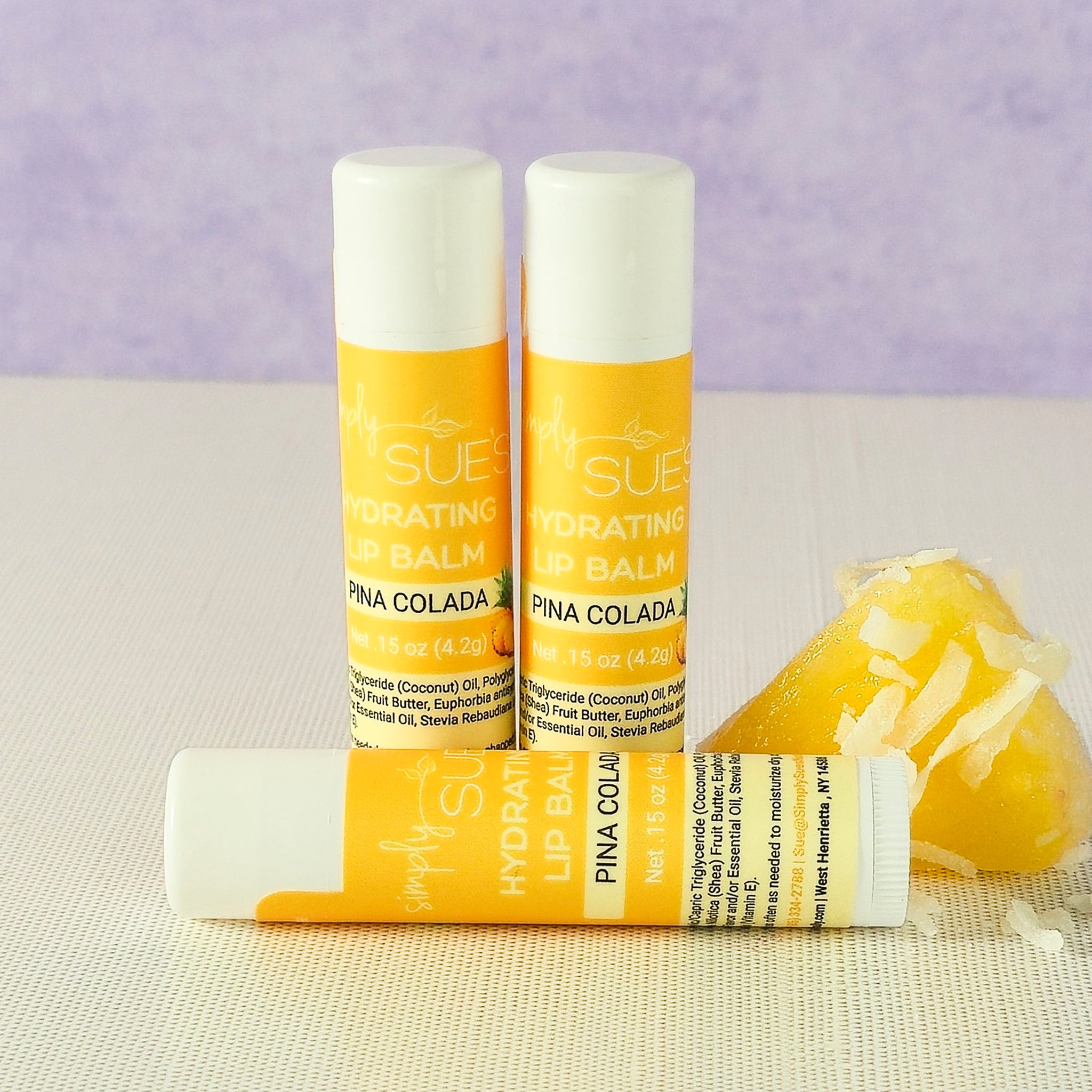 Pina colada lip balm tubes by Simply Sue’s with coconut and pineapple on a neutral background