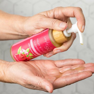 A woman pumping Fruit & Flowers Facial Cleansing Balm into her hand.