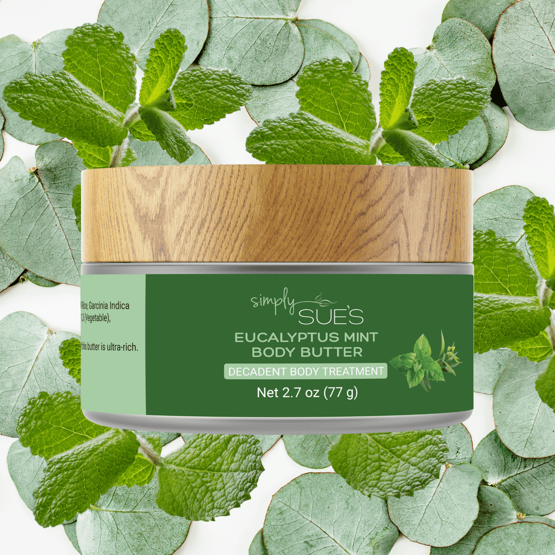 Eucalyptus Mint Body Butter in a glass jar with a bamboo cap with a background of fresh peppermint and eucalyptus leaves