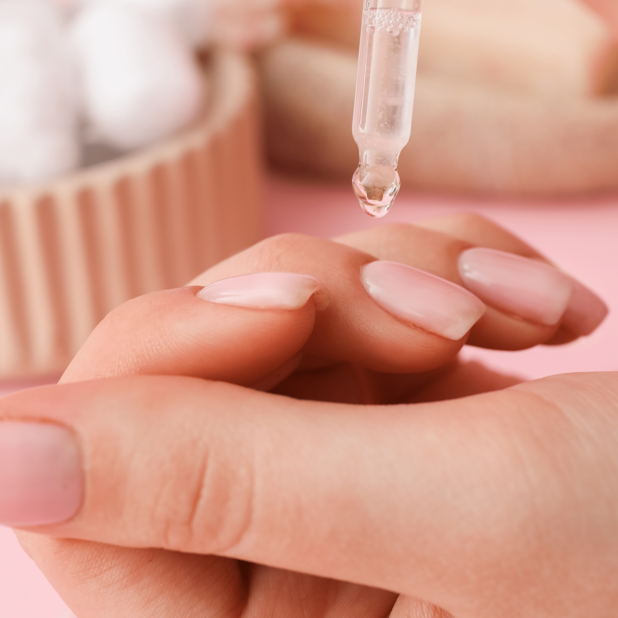 A woman in a spa setting applying cuticle oil to her cuticles.