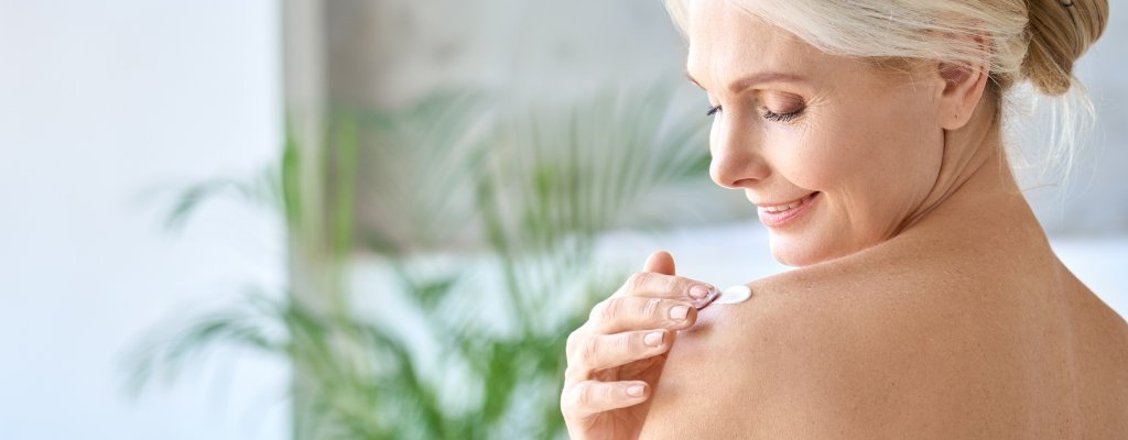 Mature woman applying Simply Sue's all natural and synthetic fragrance-free body cream to her shoulder