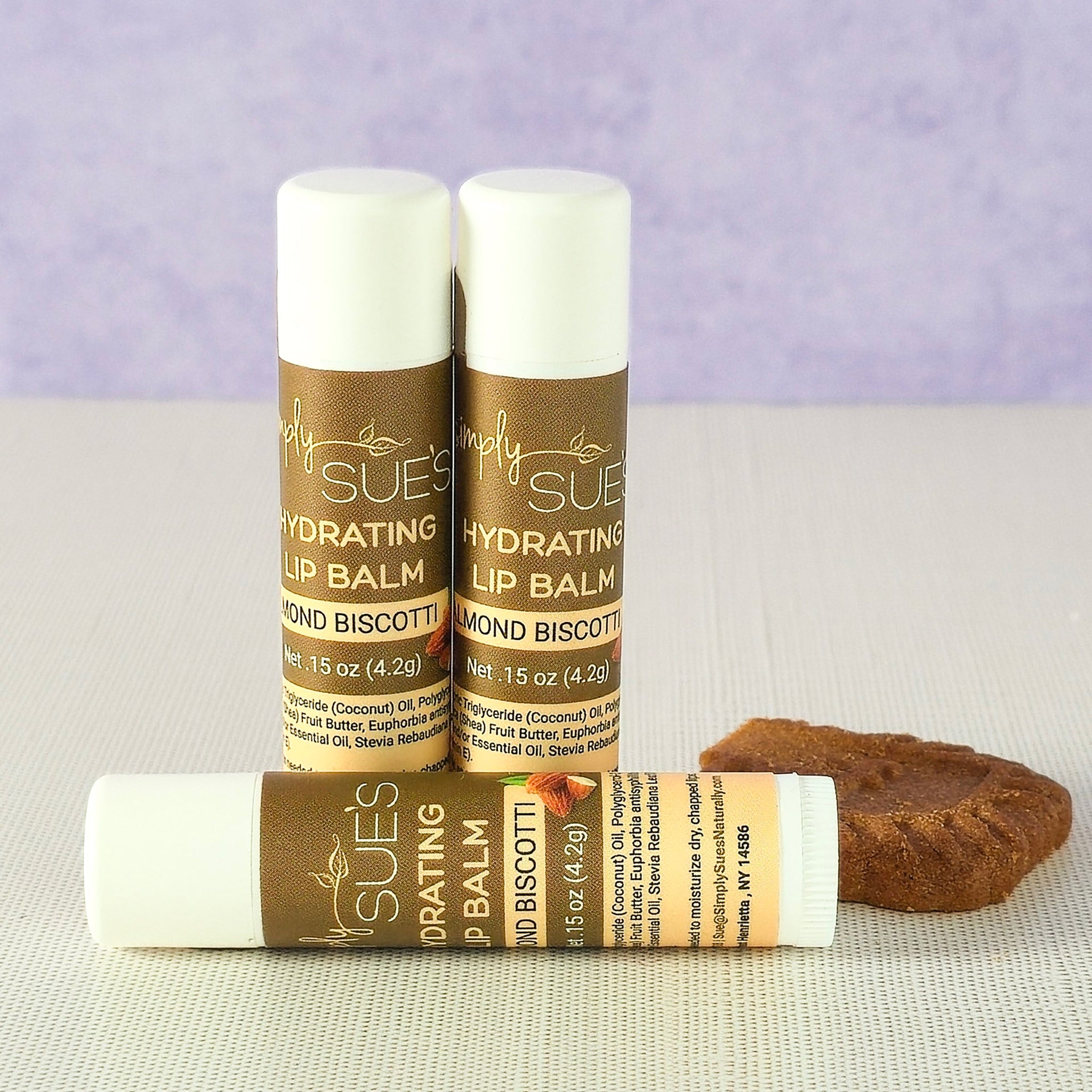 Almond biscotti lip balm tubes by Simply Sue’s with almonds on a neutral background