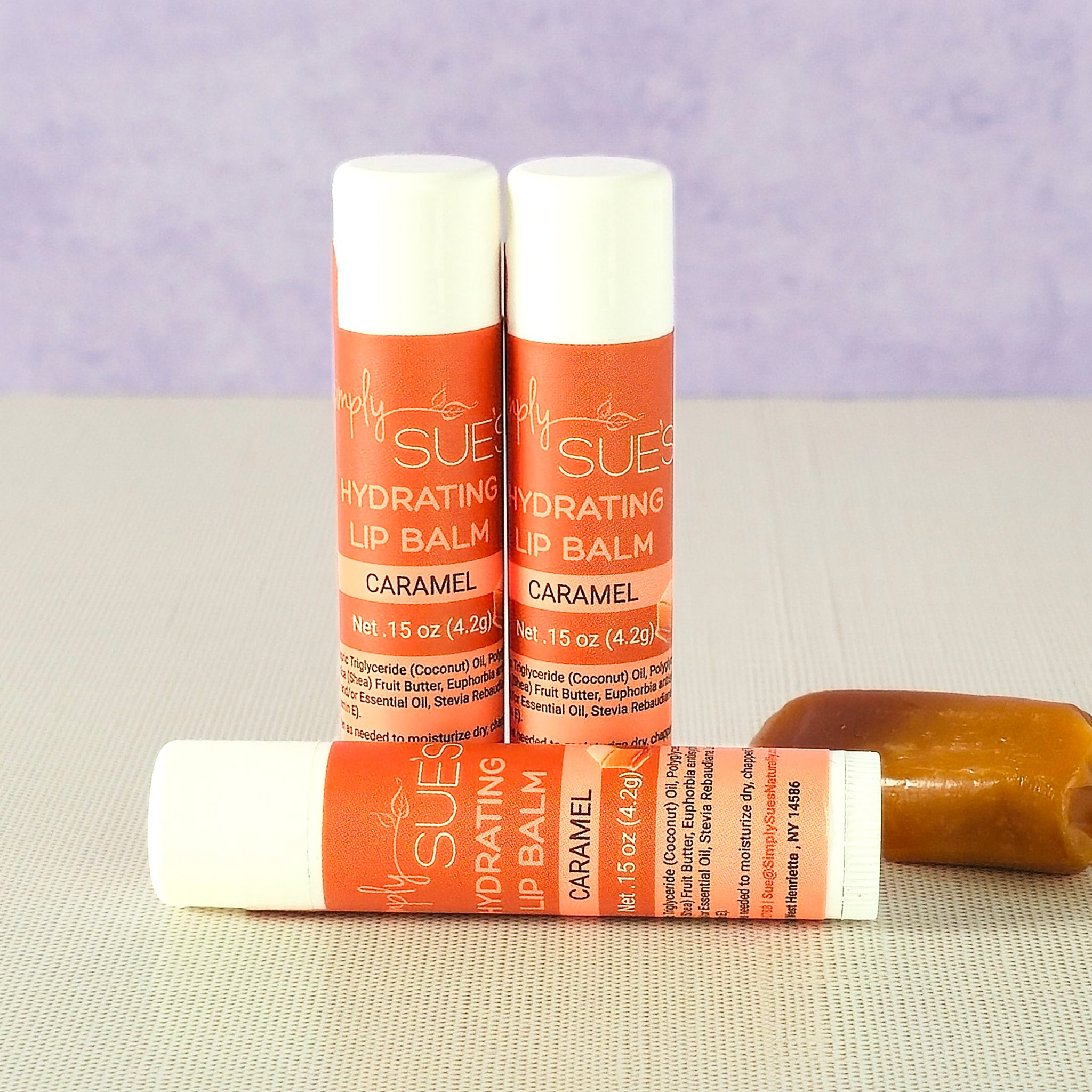 Caramel lip balm tubes by Simply Sue’s with caramel pieces on a neutral background