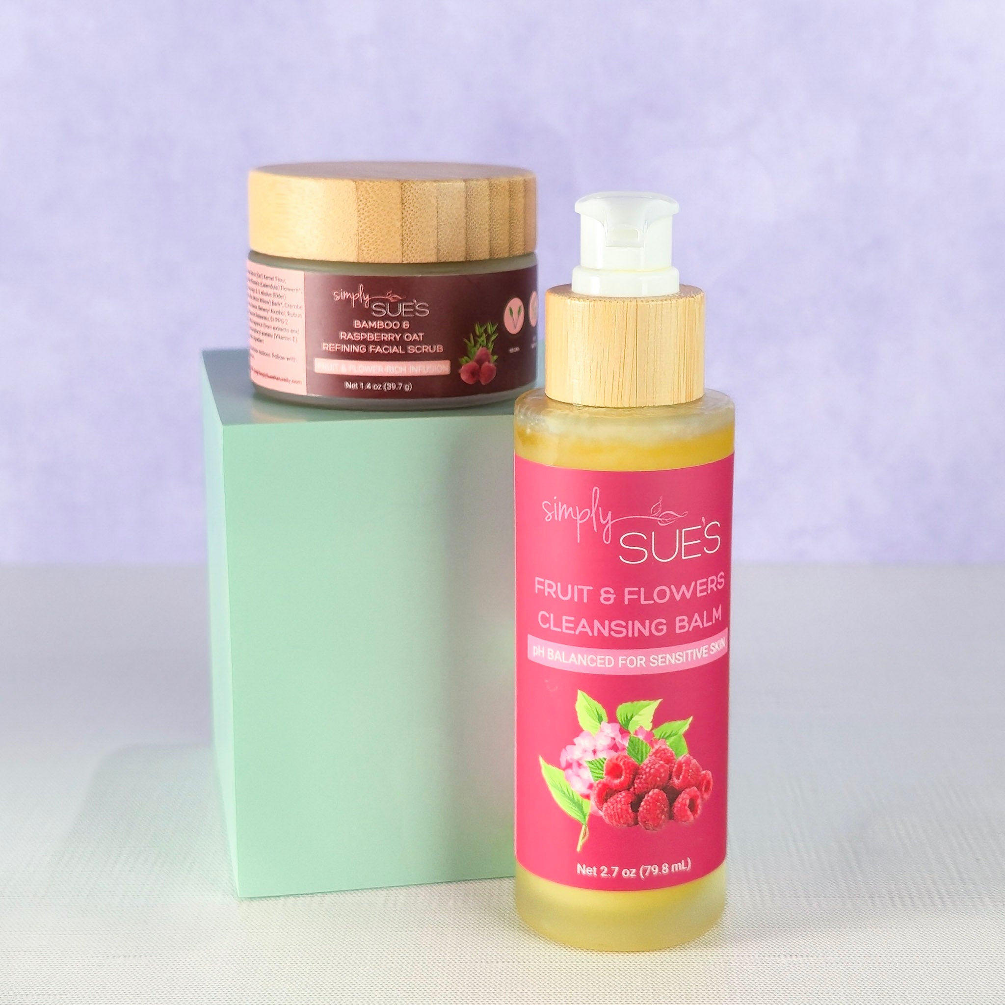 Natural skincare set with cleansing balm and exfoliating scrub in glass jars with bamboo lids on a soft purple background, gentle cleansing and smoothing ritual