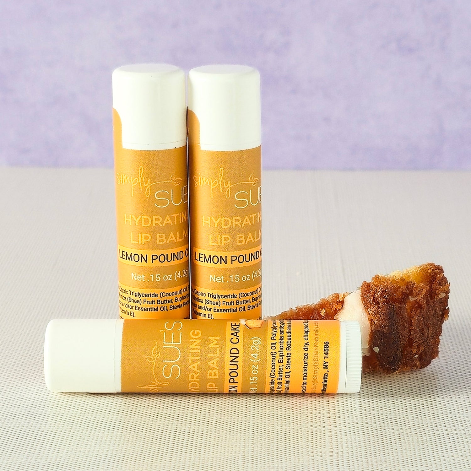 Lemon pound cake lip balm tubes by Simply Sue’s with lemon slices on a neutral background