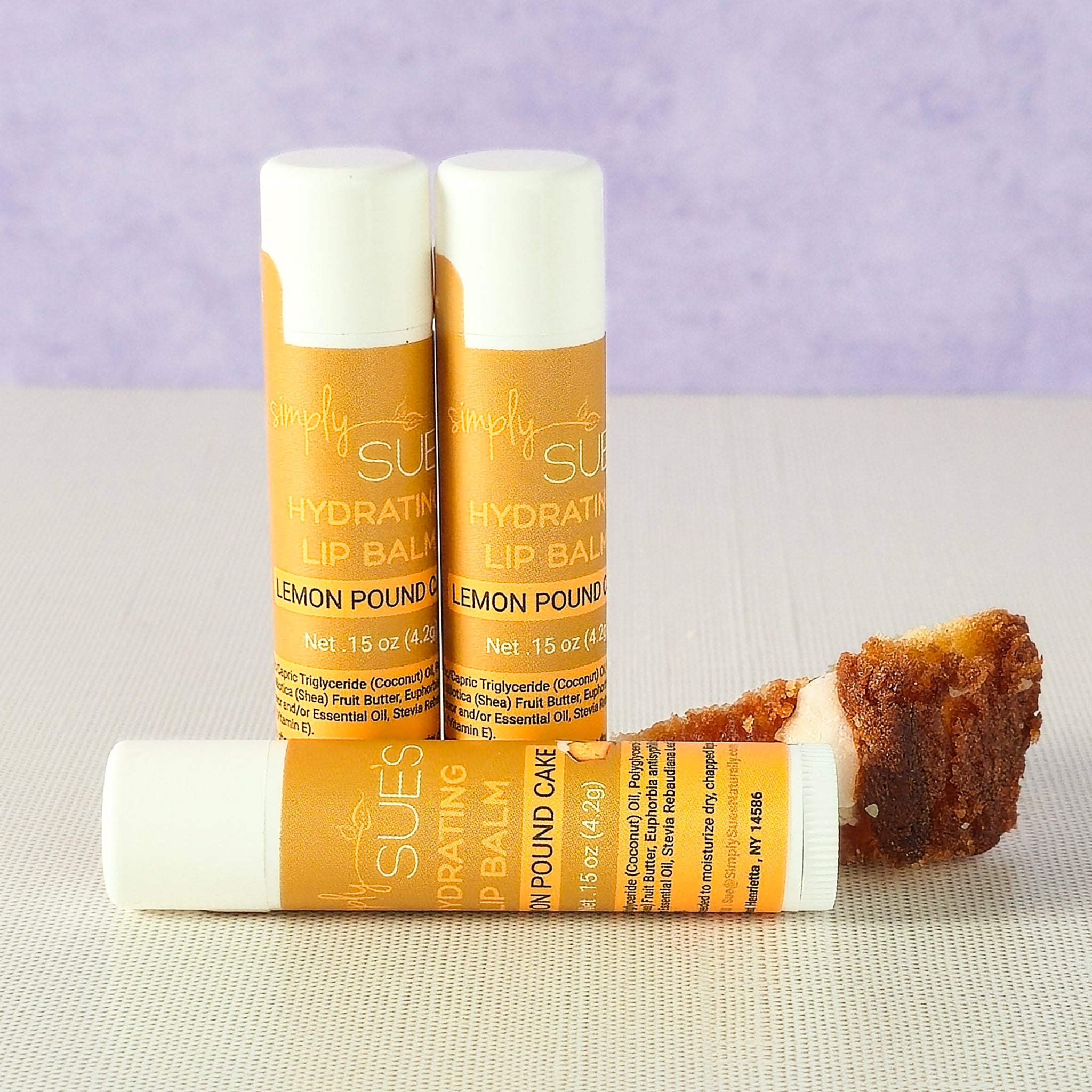 Lemon pound cake lip balm tubes by Simply Sue’s with lemon slices on a neutral background