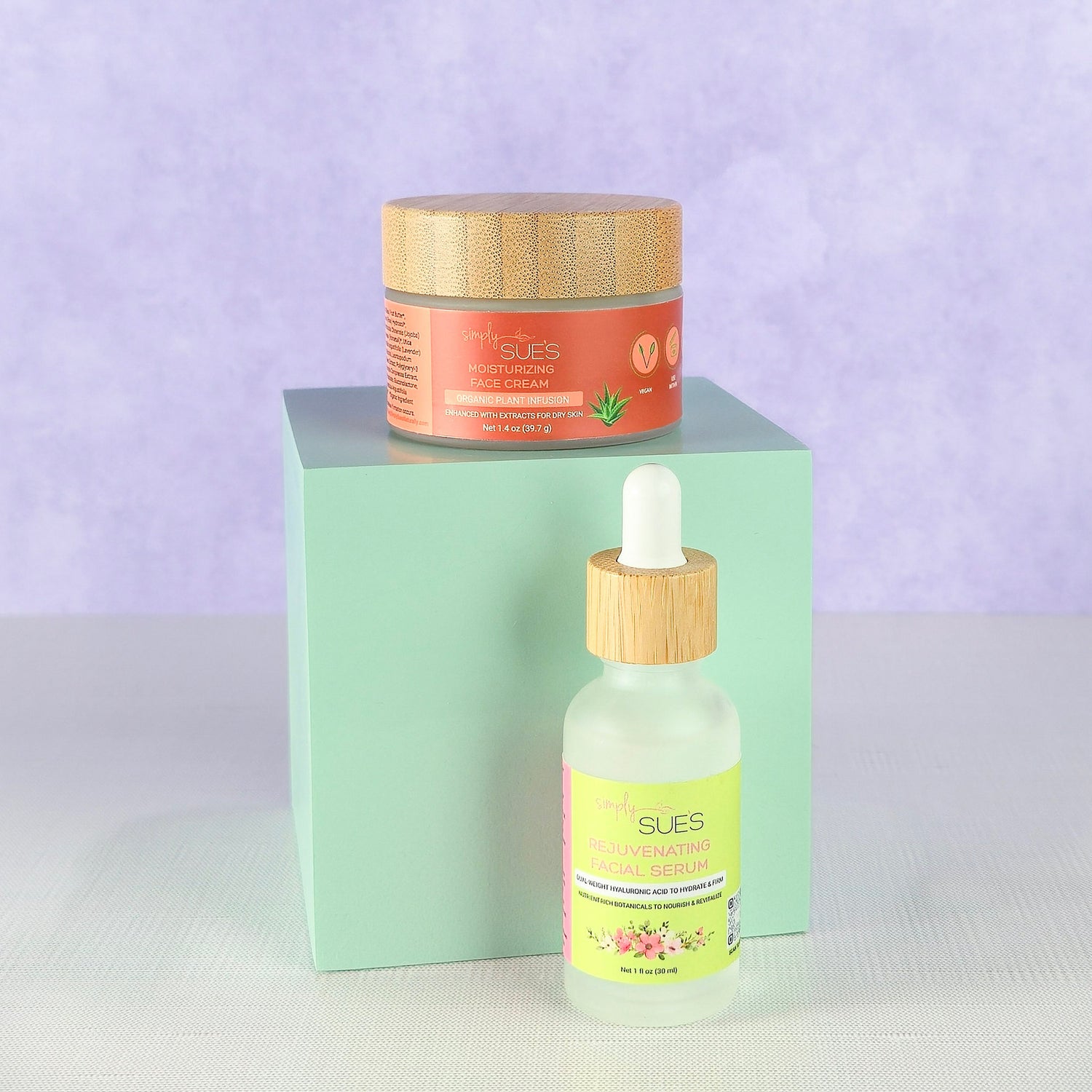 Natural skincare set with facial serum and face cream in glass bottles and jars with bamboo lids on soft purple background