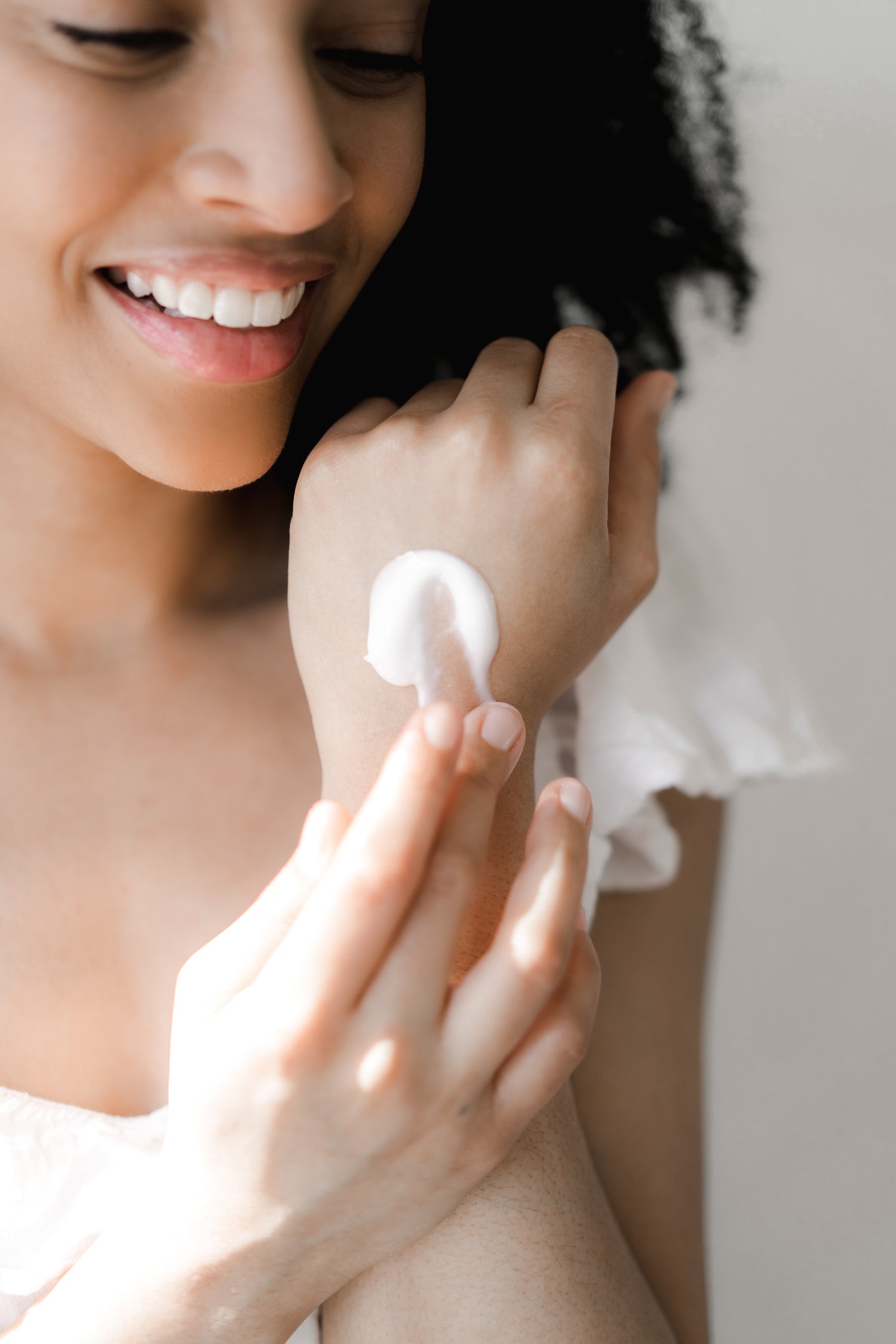 Woman applying cream to the back of her hand while smiling